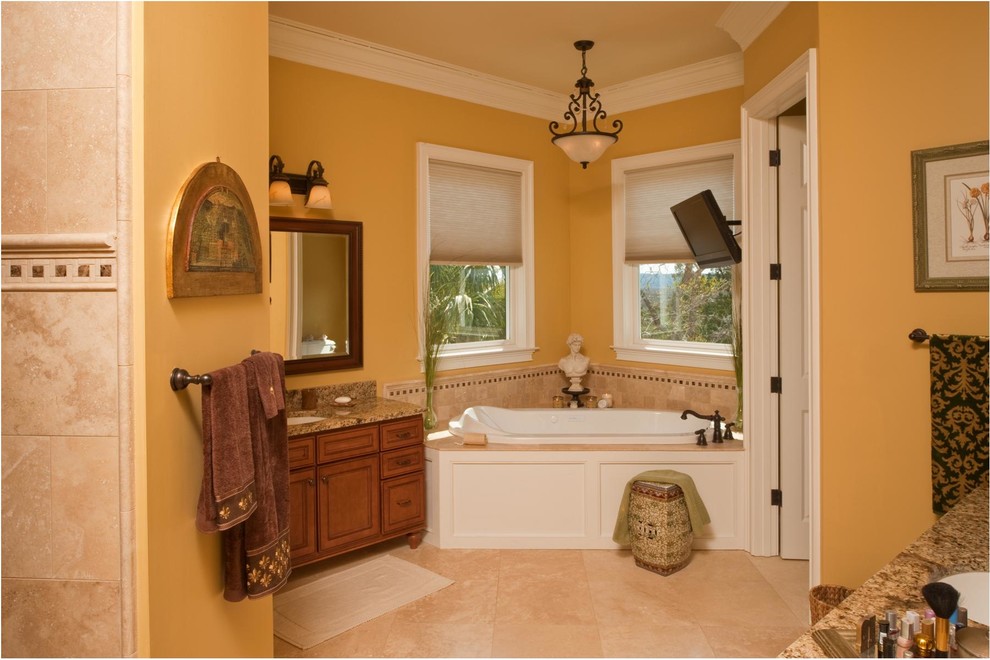 Идея дизайна: огромная главная ванная комната в классическом стиле с фасадами островного типа, фасадами цвета дерева среднего тона, столешницей из гранита, врезной раковиной, накладной ванной, коричневой плиткой, плиткой из листового камня, желтыми стенами и полом из травертина