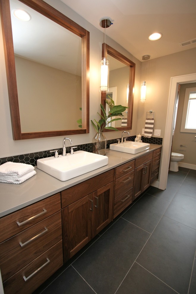 Bathroom - mid-sized transitional kids' black tile and mosaic tile porcelain tile and black floor bathroom idea in Seattle with shaker cabinets, medium tone wood cabinets, a two-piece toilet, gray walls, a vessel sink, quartz countertops, a hinged shower door and gray countertops