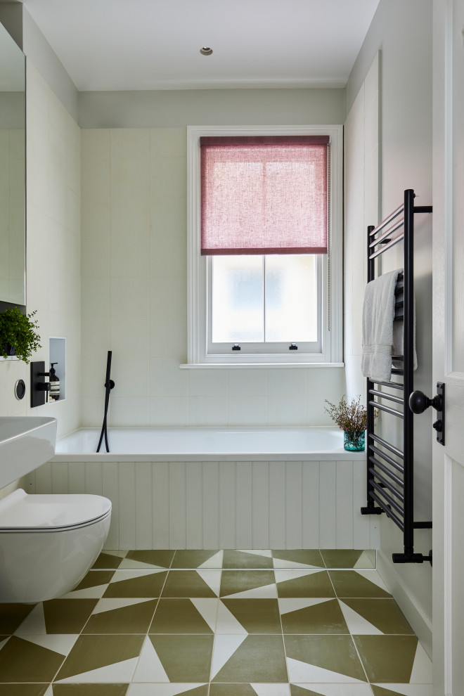 Contemporary family bathroom in London with white tiles, ceramic tiles, white walls, ceramic flooring, a wall-mounted sink, multi-coloured floors, a single sink and an alcove bath.