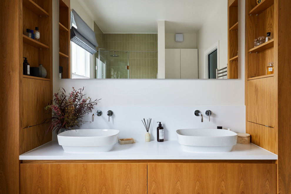 Inredning av ett modernt vit vitt en-suite badrum, med släta luckor, skåp i mellenmörkt trä, grön kakel, keramikplattor, vita väggar, bänkskiva i akrylsten och ett fristående handfat