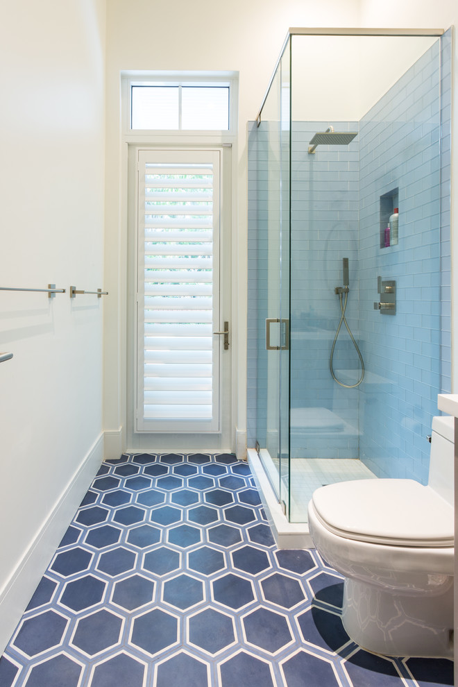 Foto på ett mellanstort maritimt badrum med dusch, med en hörndusch, en toalettstol med separat cisternkåpa, blå kakel, vita väggar, klinkergolv i porslin, ett undermonterad handfat och bänkskiva i akrylsten
