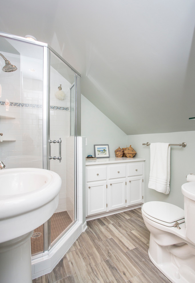 Medium sized contemporary shower room bathroom in Minneapolis with recessed-panel cabinets, white cabinets, a corner shower, white tiles, metro tiles, green walls, vinyl flooring and a pedestal sink.