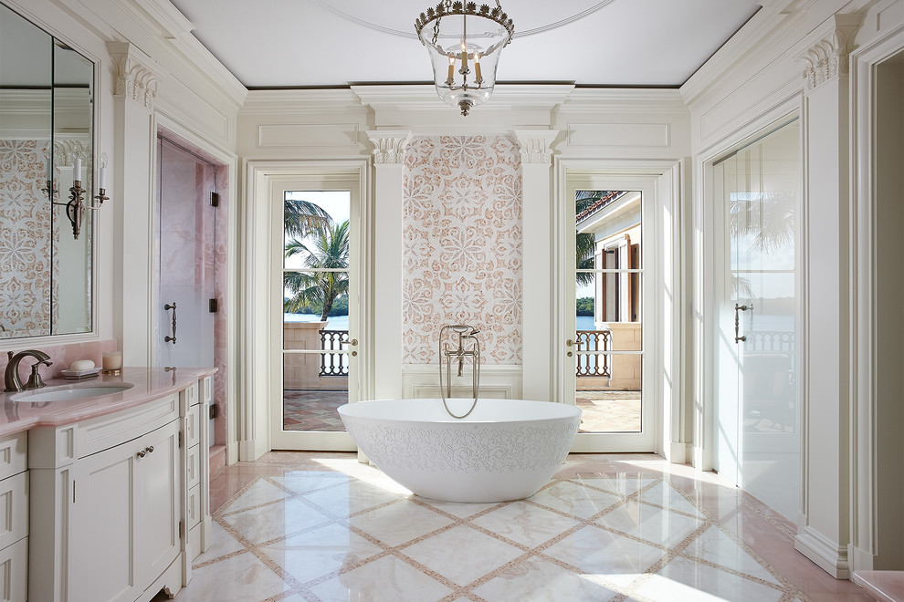 Inspiration för ett medelhavsstil rosa rosa en-suite badrum, med luckor med infälld panel, vita skåp, ett fristående badkar, vit kakel, vita väggar, ett integrerad handfat, flerfärgat golv, marmorkakel, klinkergolv i porslin och marmorbänkskiva