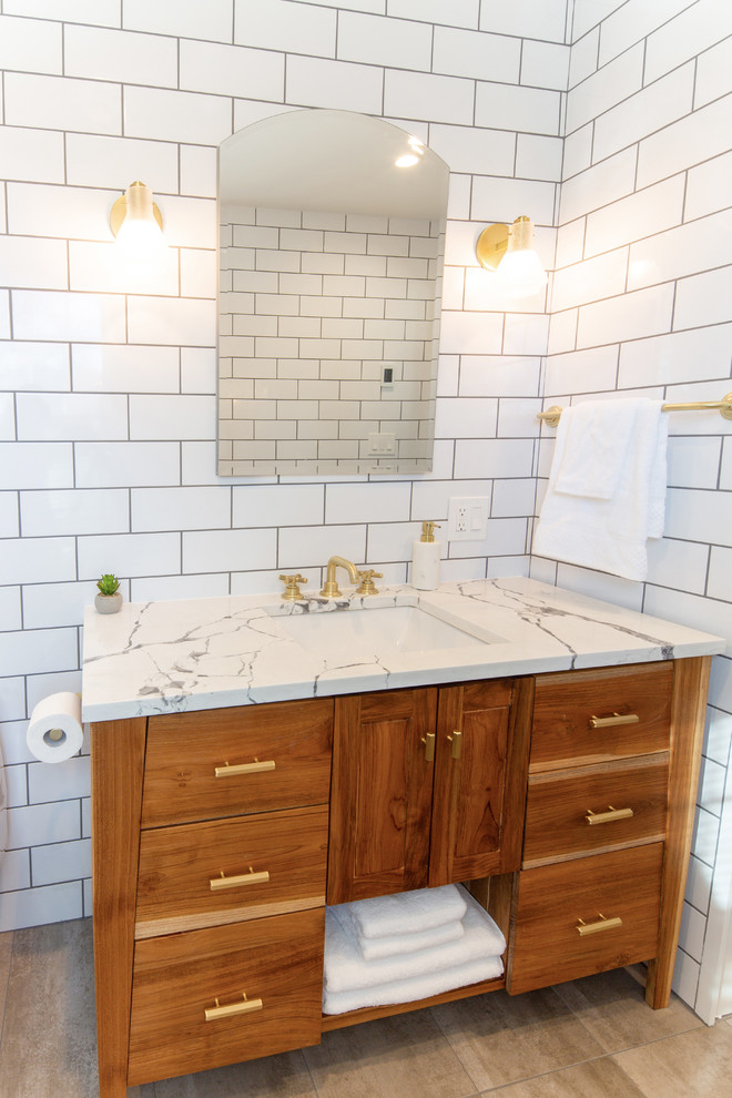 ニューヨークにある高級な中くらいなミッドセンチュリースタイルのおしゃれな浴室 (フラットパネル扉のキャビネット、中間色木目調キャビネット、アルコーブ型シャワー、分離型トイレ、白いタイル、サブウェイタイル、白い壁、コンクリートの床、アンダーカウンター洗面器、珪岩の洗面台、グレーの床、開き戸のシャワー、白い洗面カウンター) の写真