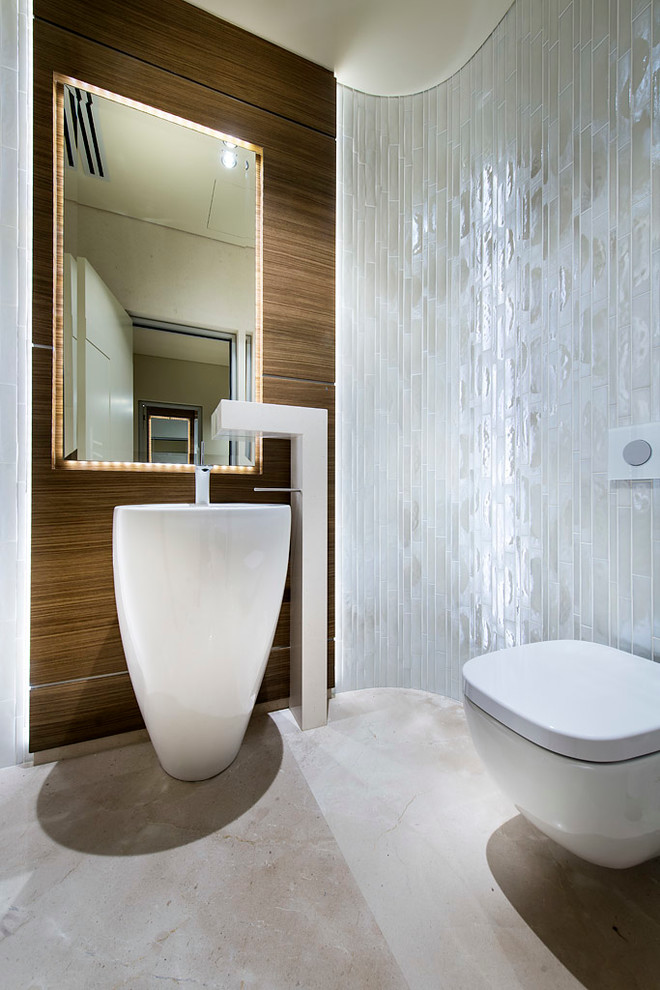 Modelo de cuarto de baño actual con lavabo con pedestal, sanitario de pared y baldosas y/o azulejos blancos