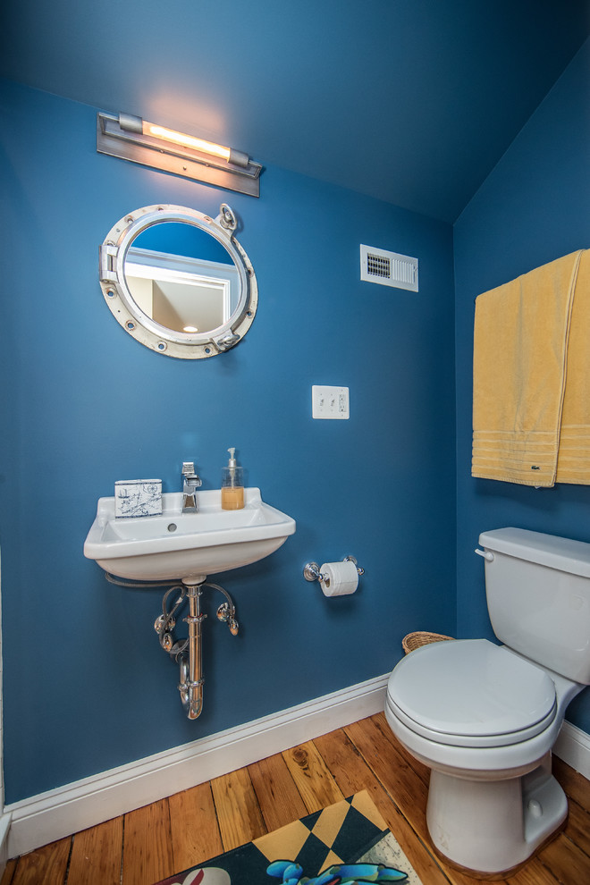 This is an example of a large rustic family bathroom in DC Metro with white tiles, an alcove shower, a two-piece toilet, ceramic tiles, blue walls, medium hardwood flooring, a wall-mounted sink and brown floors.
