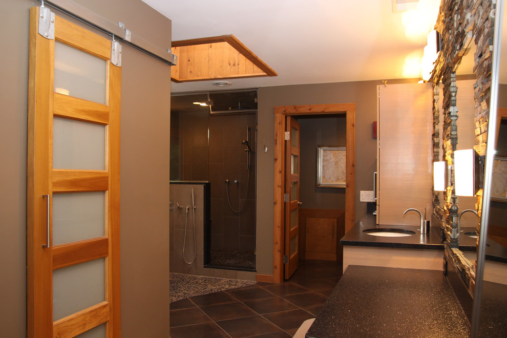 Eklektisk inredning av ett stort en-suite badrum, med ett undermonterad handfat, skåp i ljust trä, bänkskiva i kvarts, ett fristående badkar, en dubbeldusch, grå kakel, porslinskakel, grå väggar och klinkergolv i småsten
