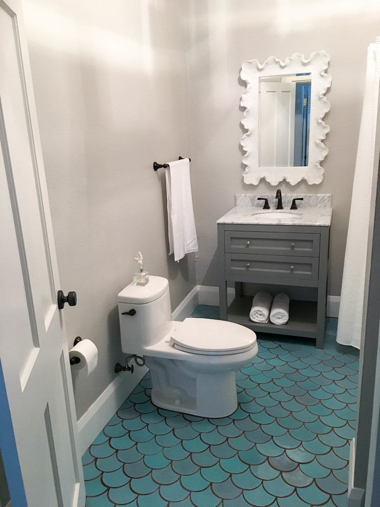 Inredning av ett maritimt litet badrum med dusch, med luckor med infälld panel, grå skåp, en toalettstol med hel cisternkåpa, grå väggar, klinkergolv i porslin, ett undermonterad handfat, marmorbänkskiva och turkost golv