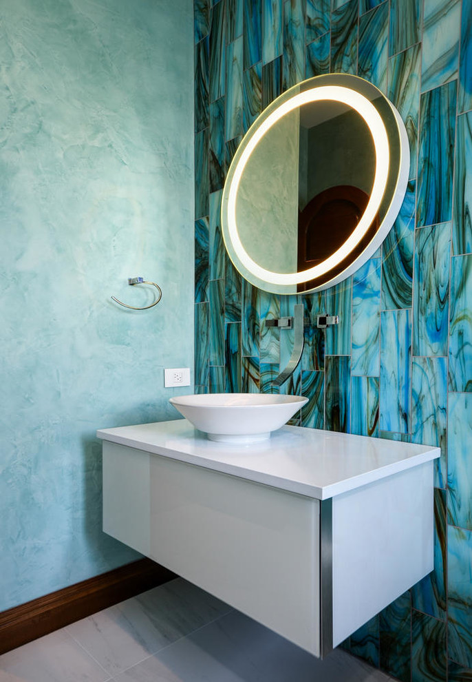 Exempel på ett mellanstort modernt badrum med dusch, med släta luckor, vita skåp, en dusch i en alkov, en vägghängd toalettstol, blå kakel, glaskakel, blå väggar, klinkergolv i porslin, ett fristående handfat och marmorbänkskiva