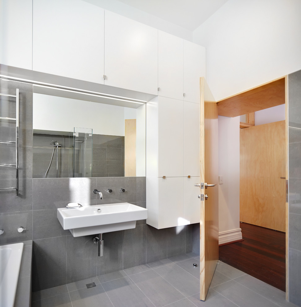 Стильный дизайн: маленькая главная ванная комната в современном стиле с душем в нише, унитазом-моноблоком, серой плиткой, плоскими фасадами, белыми фасадами, угловой ванной, керамической плиткой, белыми стенами, полом из керамической плитки, подвесной раковиной, серым полом и открытым душем для на участке и в саду - последний тренд
