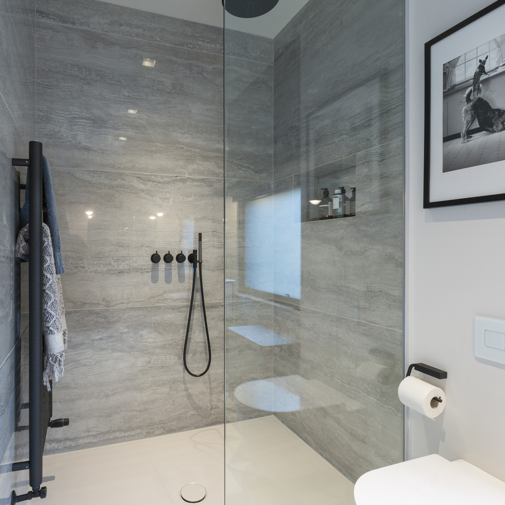 Inspiration for a medium sized contemporary ensuite bathroom in Gloucestershire with freestanding cabinets, a walk-in shower, a wall mounted toilet, grey tiles, porcelain tiles, white walls, porcelain flooring, an integrated sink, laminate worktops, an open shower, blue floors, grey cabinets and white worktops.