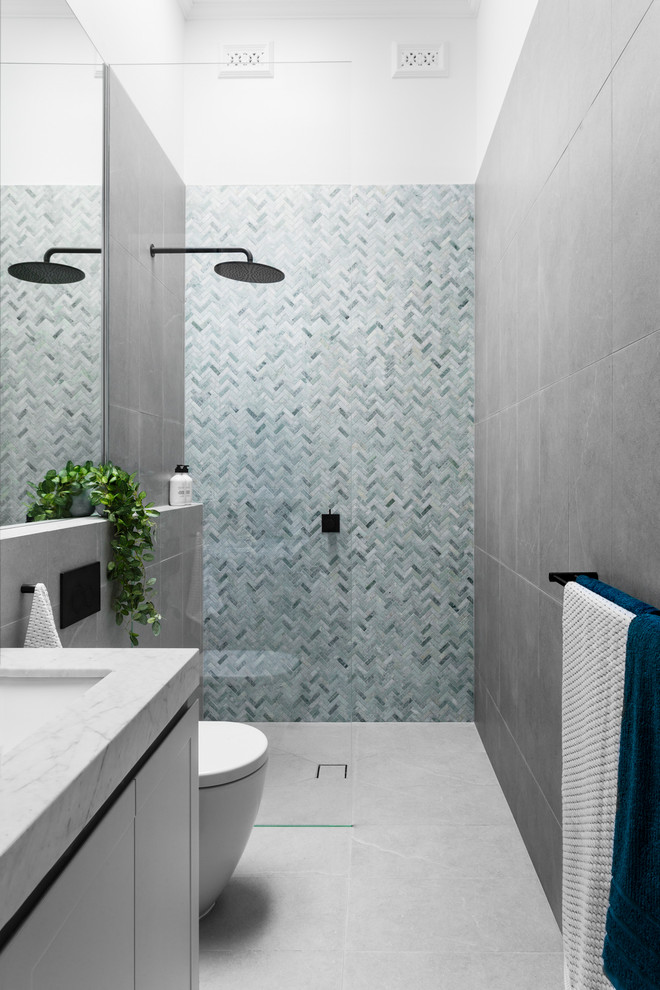 Inspiration för ett funkis badrum med dusch, med släta luckor, vita skåp, en kantlös dusch, blå kakel, grå kakel, vita väggar, ett undermonterad handfat, grått golv och med dusch som är öppen