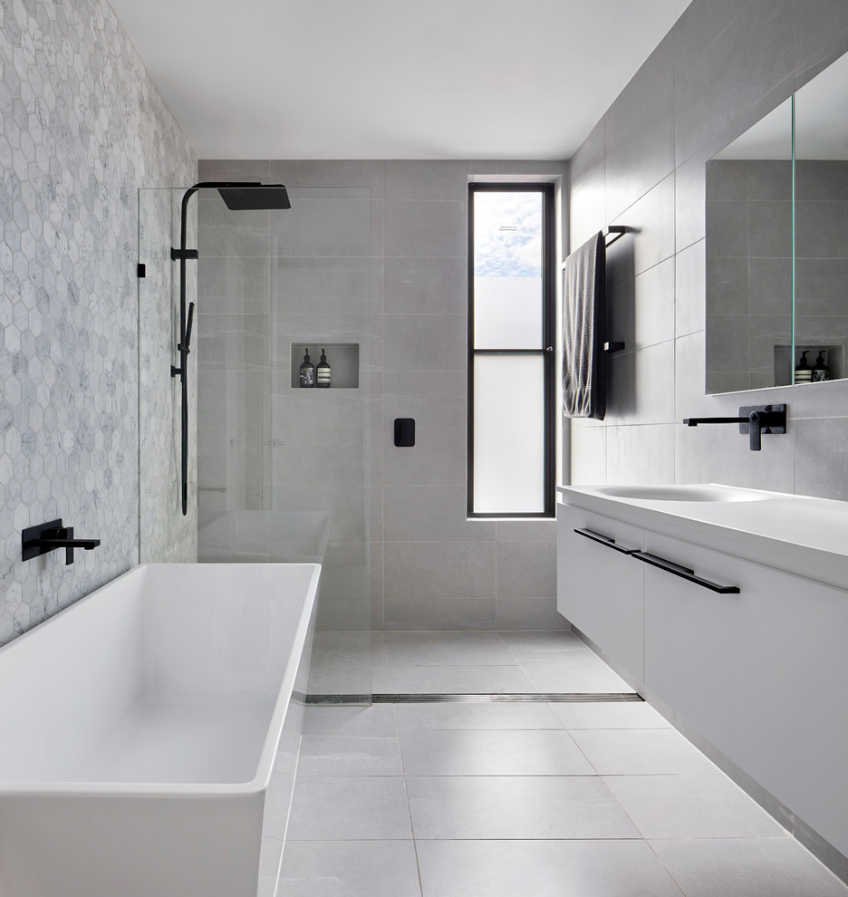 Idéer för små funkis vitt en-suite badrum, med ett fristående badkar, en öppen dusch, grå kakel, marmorkakel, klinkergolv i porslin, ett integrerad handfat, bänkskiva i akrylsten, grått golv, med dusch som är öppen, släta luckor, vita skåp och grå väggar