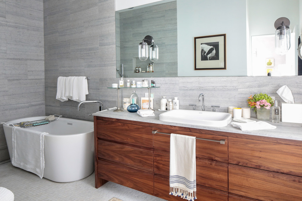 Example of a mid-sized trendy master gray tile and cement tile mosaic tile floor and white floor drop-in bathtub design in New York with flat-panel cabinets, medium tone wood cabinets, gray walls, an undermount sink, marble countertops and white countertops