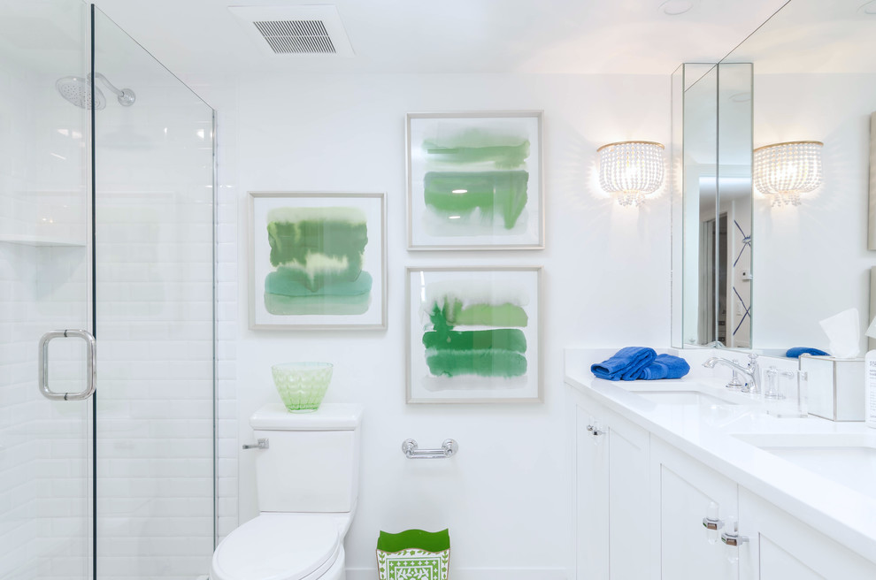 マイアミにある中くらいなビーチスタイルのおしゃれなバスルーム (浴槽なし) (シェーカースタイル扉のキャビネット、白いキャビネット、一体型トイレ	、白い壁、セラミックタイルの床、アンダーカウンター洗面器、クオーツストーンの洗面台、白い床、開き戸のシャワー、白い洗面カウンター、アルコーブ型シャワー) の写真