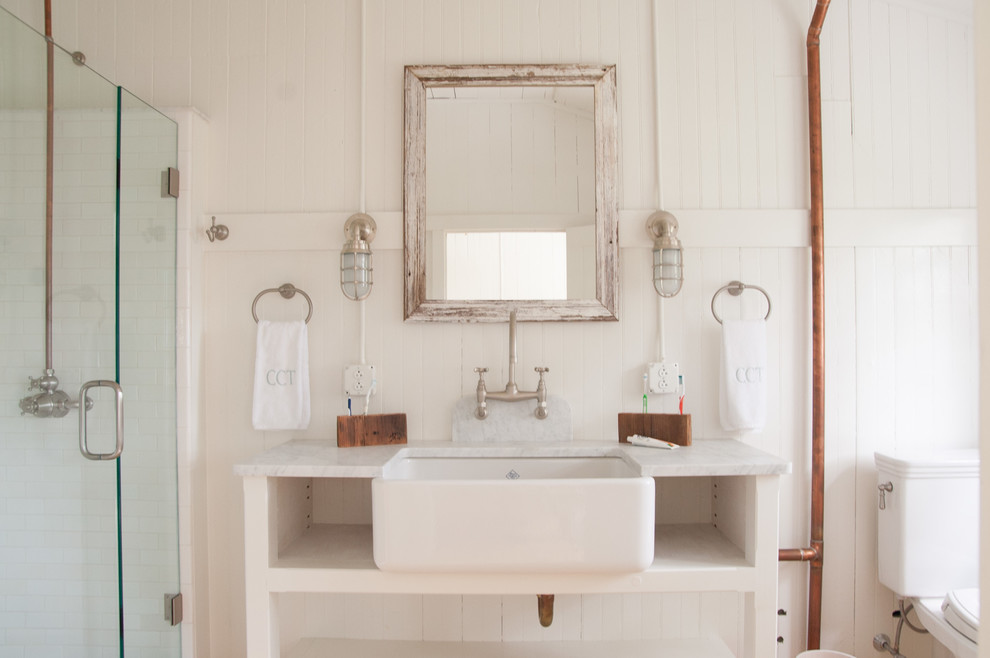 Foto på ett mellanstort maritimt en-suite badrum, med öppna hyllor, vita skåp, en dusch i en alkov, en toalettstol med separat cisternkåpa, vit kakel, tunnelbanekakel, vita väggar och marmorbänkskiva