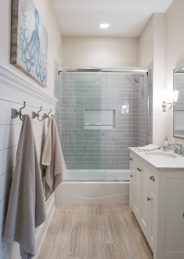 Bild på ett maritimt badrum med dusch, med luckor med infälld panel, vita skåp, ett badkar i en alkov, en dusch/badkar-kombination, grå kakel, glaskakel, beige väggar, ett undermonterad handfat, beiget golv och dusch med skjutdörr