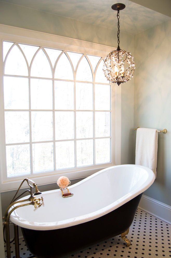Cette image montre une salle de bain principale victorienne de taille moyenne avec un placard à porte shaker, des portes de placard blanches, une baignoire sur pieds, un carrelage noir et blanc, des carreaux de porcelaine, un mur bleu, un sol en carrelage de terre cuite et un lavabo de ferme.