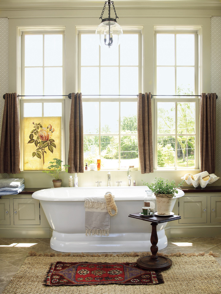 Réalisation d'une salle de bain champêtre avec une baignoire indépendante, un mur beige et un sol en ardoise.