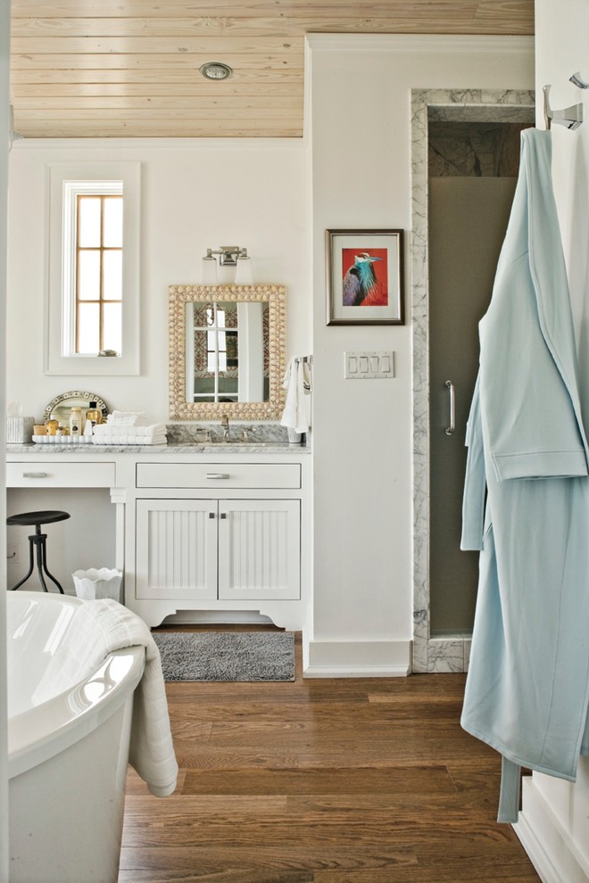 На фото: ванная комната в морском стиле с врезной раковиной, фасадами с утопленной филенкой, белыми фасадами, ванной на ножках, душем в нише, белыми стенами и паркетным полом среднего тона с