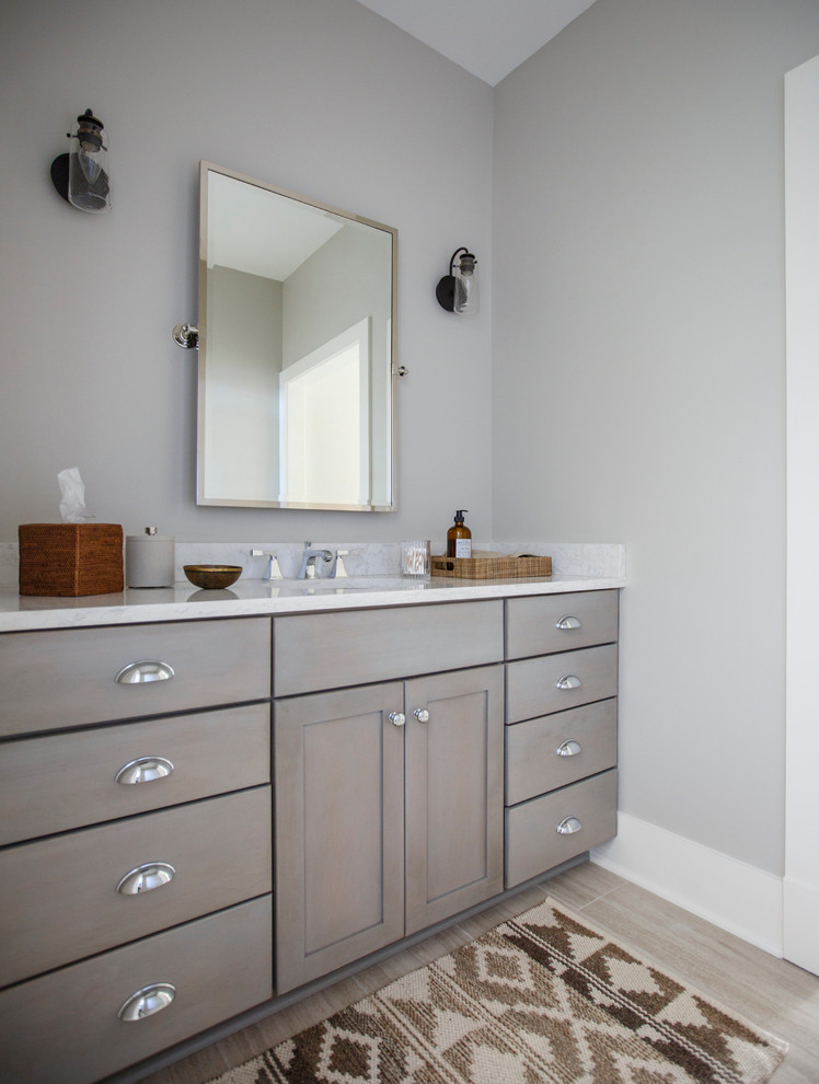 Diseño de cuarto de baño clásico de tamaño medio con lavabo bajoencimera, armarios estilo shaker, puertas de armario de madera oscura, paredes grises y encimera de acrílico