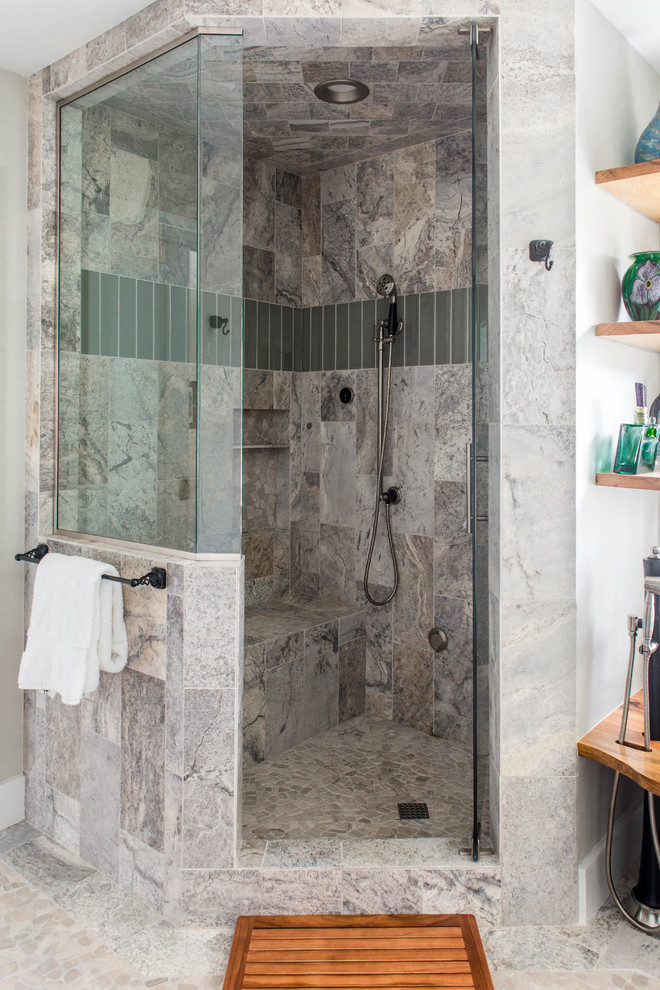 This is an example of a large contemporary ensuite bathroom in Austin with shaker cabinets, medium wood cabinets, a freestanding bath, a corner shower, grey tiles, marble tiles, beige walls, marble flooring, a vessel sink, granite worktops, beige floors, a hinged door and black worktops.