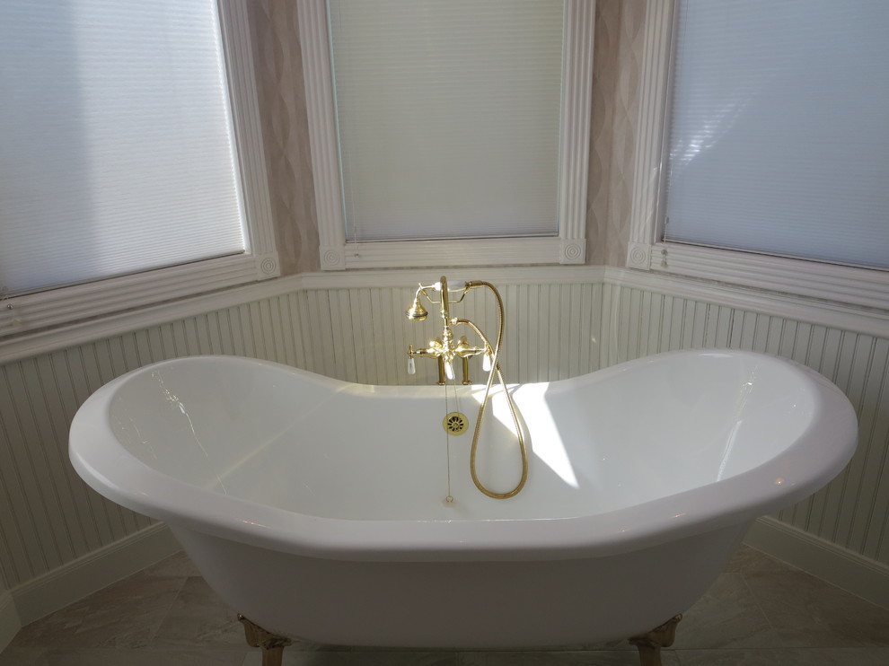 Cette image montre une salle de bain principale traditionnelle de taille moyenne avec une baignoire sur pieds, un carrelage beige, des carreaux de porcelaine, un mur gris et un sol en carrelage de porcelaine.