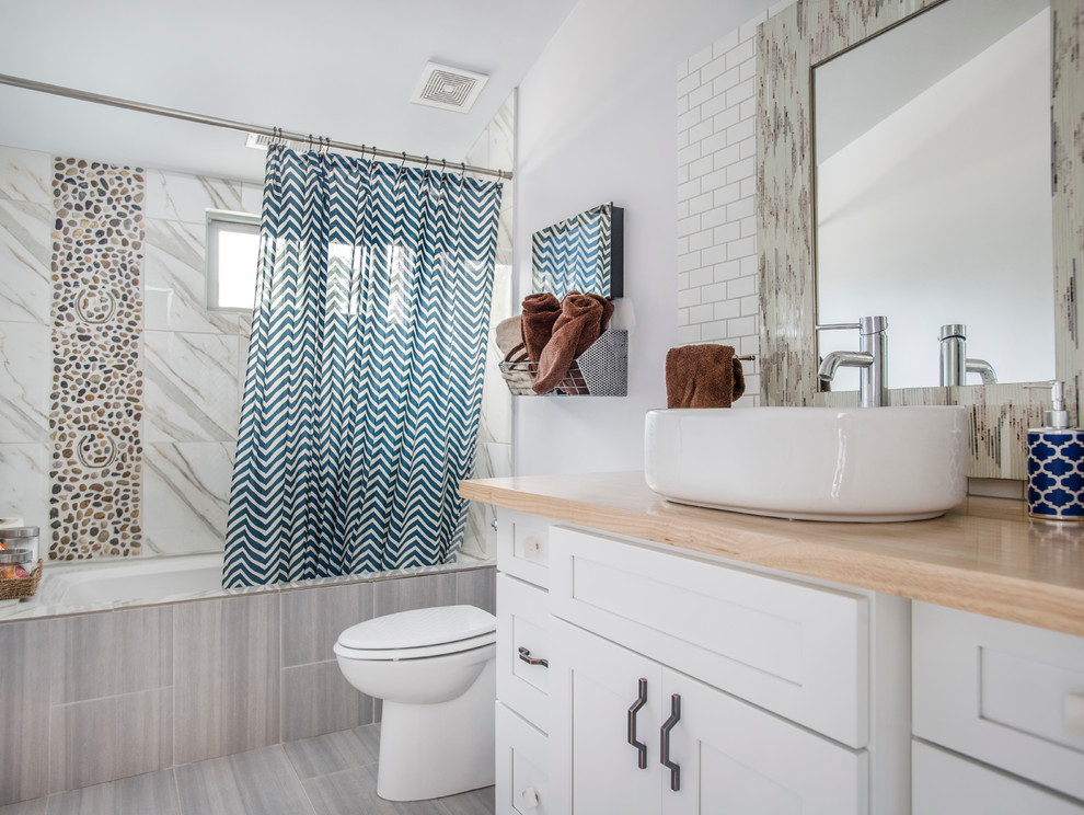 Foto på ett mellanstort lantligt badrum, med skåp i shakerstil, vita skåp, en dusch/badkar-kombination, vita väggar, laminatgolv, ett fristående handfat, träbänkskiva, ett badkar i en alkov, vit kakel och dusch med duschdraperi