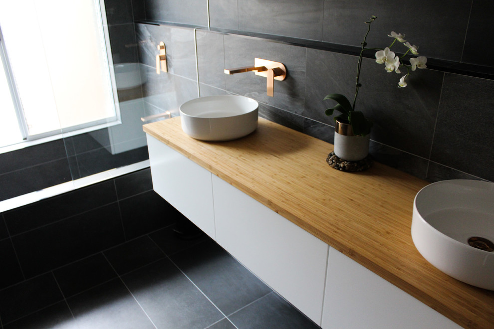 Design ideas for a medium sized contemporary family bathroom in Perth with freestanding cabinets, white cabinets, an alcove bath, a shower/bath combination, black tiles, porcelain tiles, black walls, porcelain flooring, a vessel sink, wooden worktops, black floors and multi-coloured worktops.