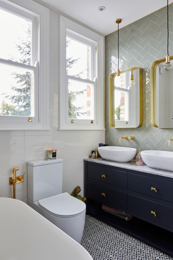 Inspiration for a mid-sized transitional master green tile and white tile multicolored floor and double-sink freestanding bathtub remodel in London with flat-panel cabinets, blue cabinets, a one-piece toilet, a vessel sink, gray countertops and a built-in vanity