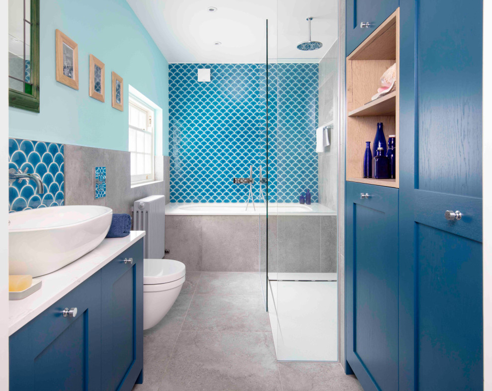 Photo of a medium sized nautical family bathroom in London with blue walls, slate flooring, a vessel sink, grey floors, shaker cabinets, blue cabinets, a built-in bath, a walk-in shower, a wall mounted toilet, blue tiles, an open shower, white worktops, a single sink and a freestanding vanity unit.