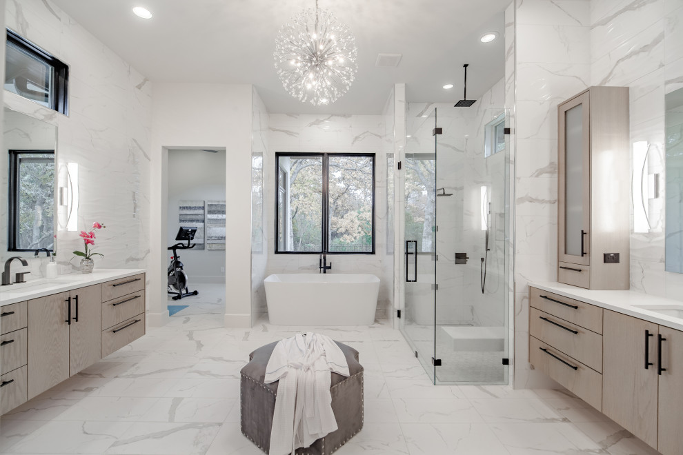 Inredning av ett klassiskt mycket stort vit vitt en-suite badrum, med släta luckor, skåp i ljust trä, ett fristående badkar, en kantlös dusch, vit kakel, marmorkakel, vita väggar, marmorgolv, ett undermonterad handfat, vitt golv och dusch med gångjärnsdörr