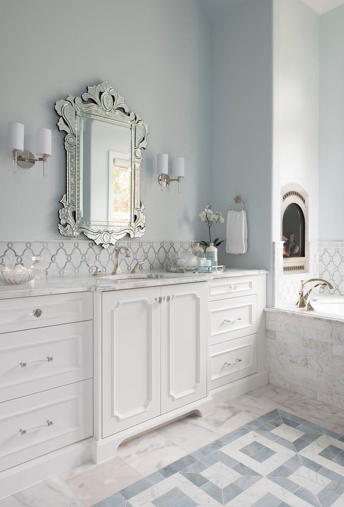 На фото: ванная комната в средиземноморском стиле с фасадами с утопленной филенкой, белыми фасадами, полновстраиваемой ванной, мраморным полом, врезной раковиной и разноцветным полом с
