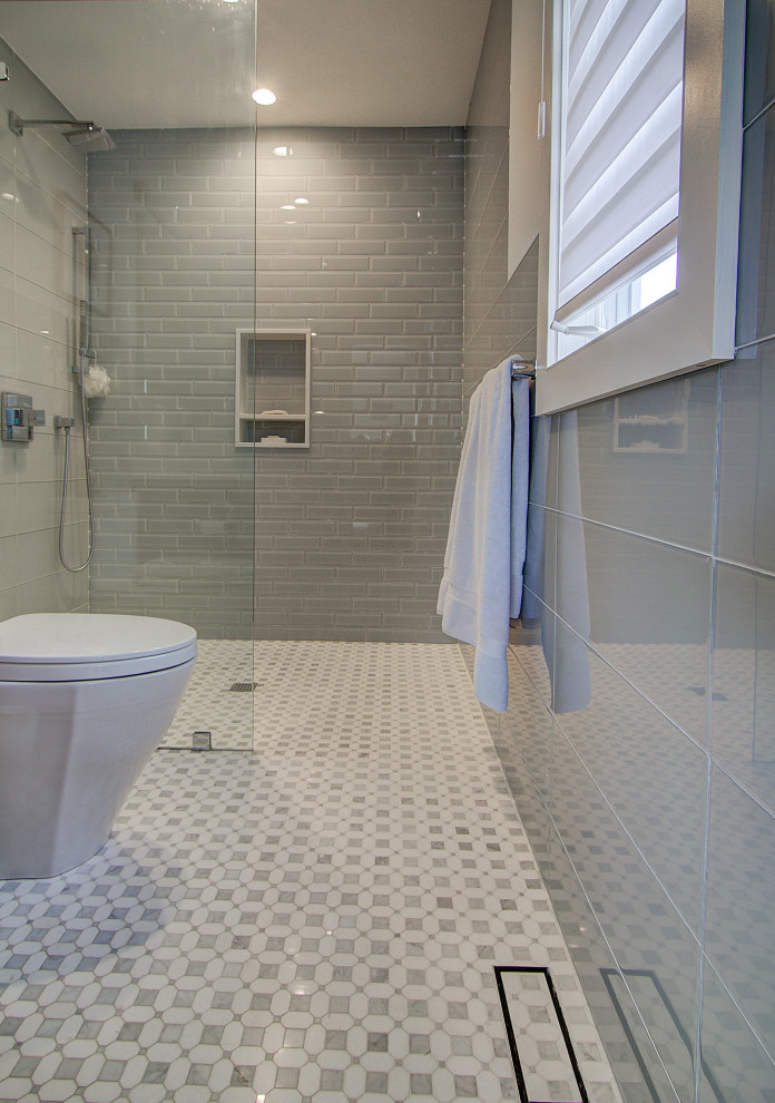 Modern inredning av ett litet vit vitt en-suite badrum, med släta luckor, bruna skåp, en kantlös dusch, en toalettstol med hel cisternkåpa, grå kakel, glaskakel, grå väggar, marmorgolv, ett undermonterad handfat, bänkskiva i kvartsit, flerfärgat golv och med dusch som är öppen