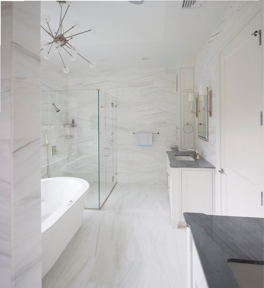 Photo of a large traditional ensuite bathroom in New York with recessed-panel cabinets, white cabinets, a freestanding bath, a built-in shower, a one-piece toilet, white tiles, stone tiles, white walls, marble flooring, a submerged sink, marble worktops and a hinged door.