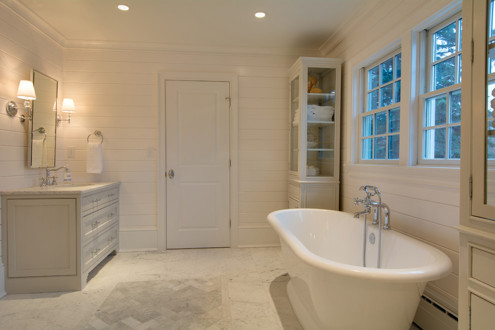 Cette photo montre une grande salle de bain principale chic avec un lavabo encastré, un placard à porte affleurante, des portes de placard grises, un plan de toilette en marbre, une baignoire indépendante, une douche ouverte, WC séparés, un carrelage blanc, un carrelage de pierre, un mur blanc et un sol en marbre.