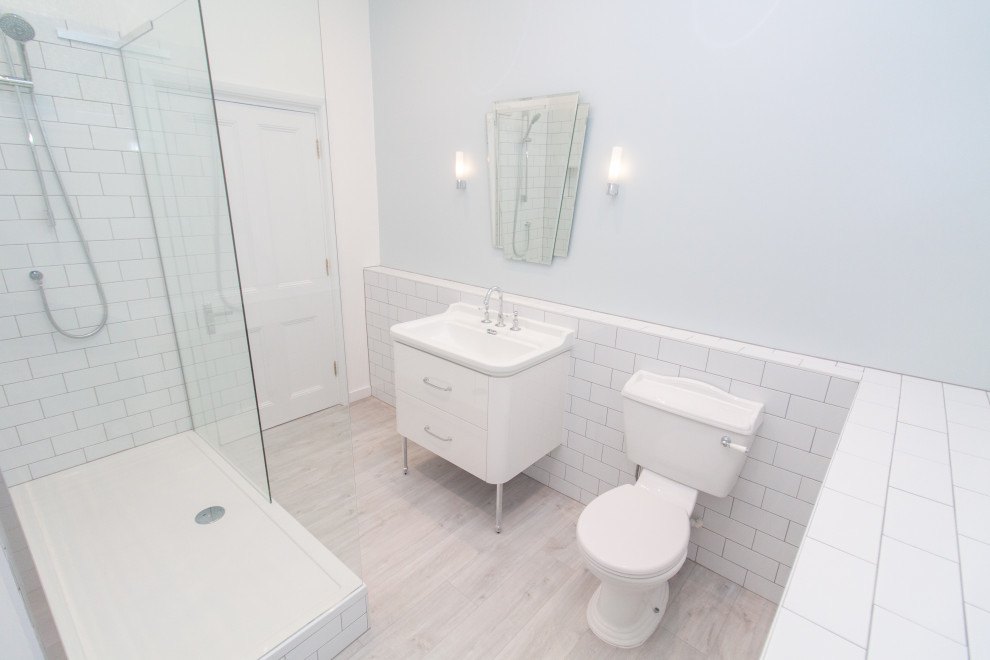 Photo of a medium sized traditional family bathroom in Other with flat-panel cabinets, white cabinets, a walk-in shower, white tiles, ceramic tiles, white walls, vinyl flooring, a wall-mounted sink, grey floors, an open shower, a single sink and a freestanding vanity unit.