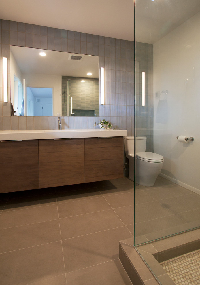 Exemple d'une salle de bain principale rétro en bois brun de taille moyenne avec un placard à porte plane, une douche d'angle, WC à poser, un carrelage bleu, des carreaux de céramique, un mur blanc, un sol en carrelage de porcelaine, un lavabo intégré, un plan de toilette en quartz modifié, un sol gris et une cabine de douche à porte battante.