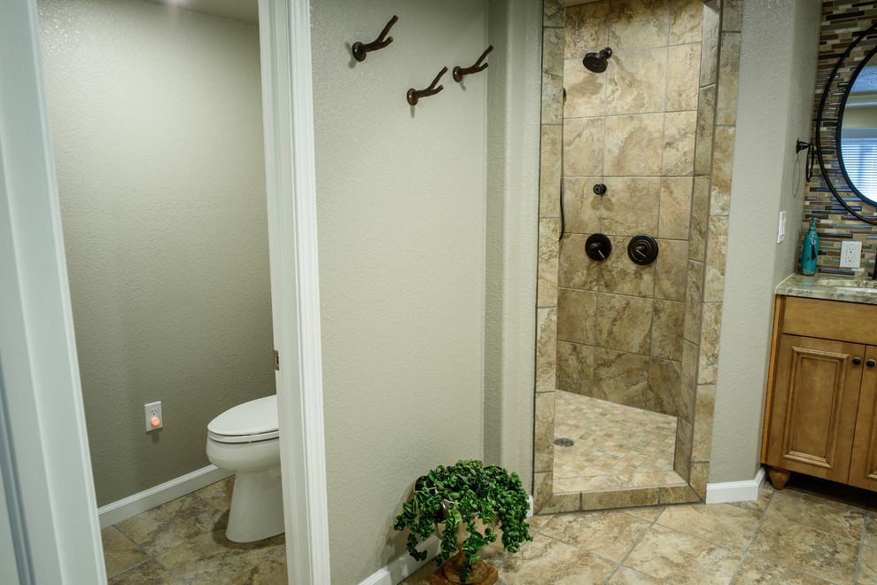 Exemple d'une grande salle de bain principale sud-ouest américain en bois brun avec un placard en trompe-l'oeil, une douche ouverte, WC à poser, un carrelage multicolore, des plaques de verre, un mur beige, un sol en carrelage de porcelaine, un lavabo encastré et un plan de toilette en granite.