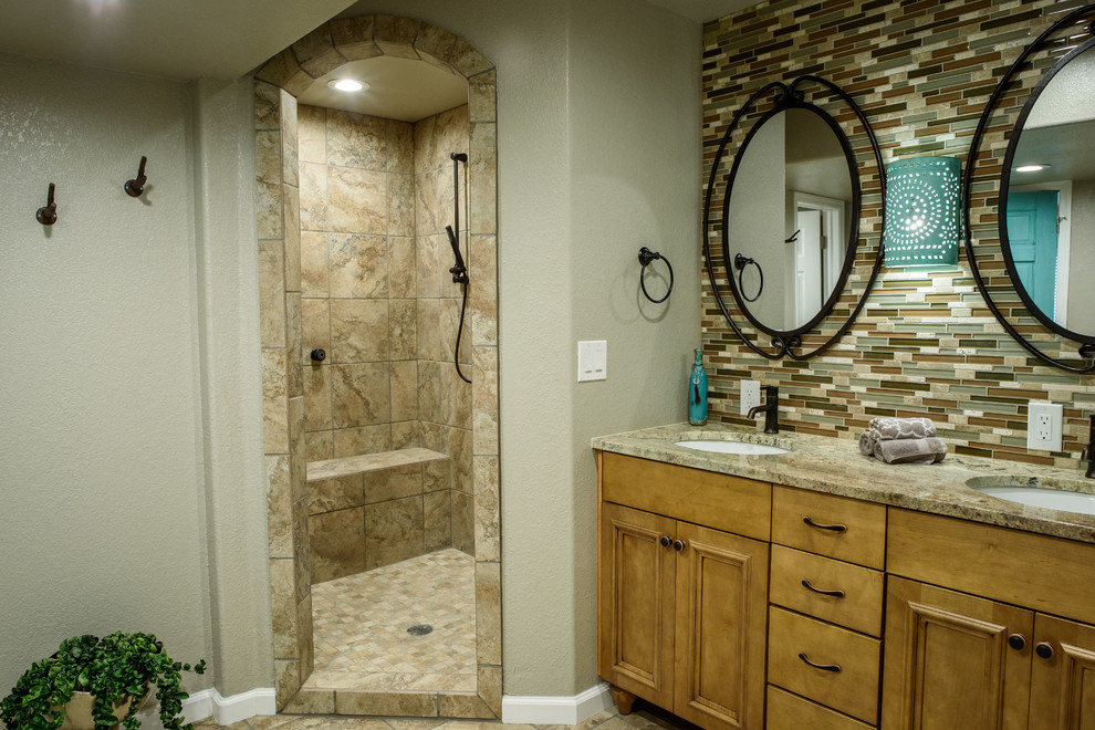 Doorless shower - large southwestern master multicolored tile and glass sheet porcelain tile doorless shower idea in Denver with furniture-like cabinets, medium tone wood cabinets, a one-piece toilet, beige walls, an undermount sink and granite countertops