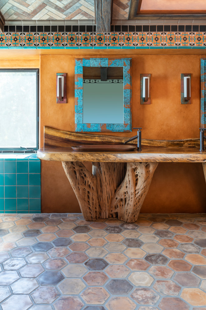 Mediterranes Badezimmer mit hellen Holzschränken, freistehender Badewanne, blauen Fliesen, Keramikfliesen, Betonboden, Einbauwaschbecken, Waschtisch aus Holz, buntem Boden, Falttür-Duschabtrennung und brauner Waschtischplatte in Los Angeles