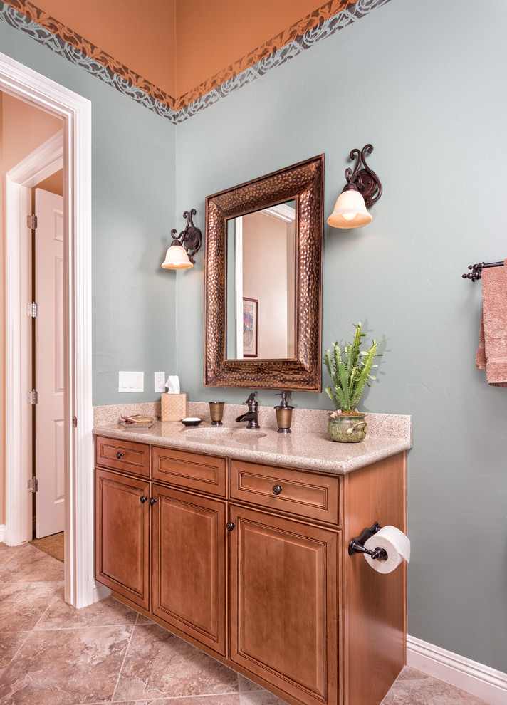 Immagine di una stanza da bagno con doccia mediterranea di medie dimensioni con lavabo integrato, ante con bugna sagomata, ante in legno chiaro, pareti blu e pavimento in gres porcellanato