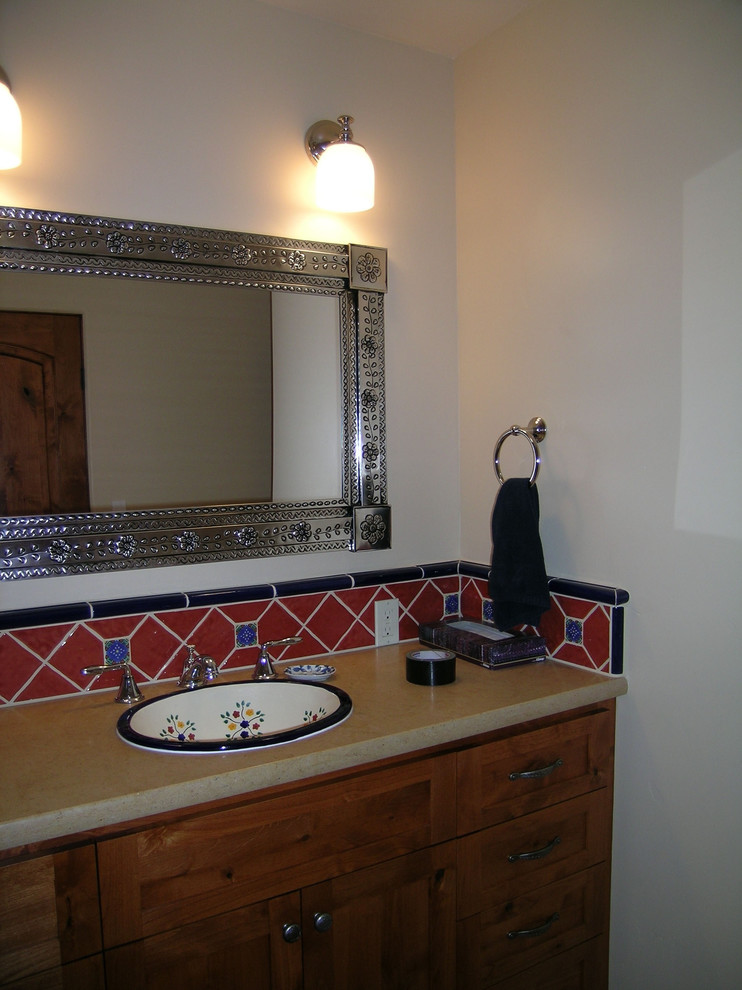 Cette image montre une petite salle de bain sud-ouest américain en bois foncé avec un lavabo posé, un plan de toilette en calcaire, un carrelage rouge, des carreaux de céramique, un mur blanc, une baignoire en alcôve, WC à poser, un sol en carrelage de céramique et un placard à porte shaker.