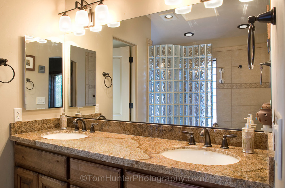 Cette image montre une grande salle de bain principale sud-ouest américain avec un lavabo posé, un placard à porte plane, un plan de toilette en marbre, une douche ouverte, WC à poser, un carrelage de pierre, un mur beige et un sol en marbre.