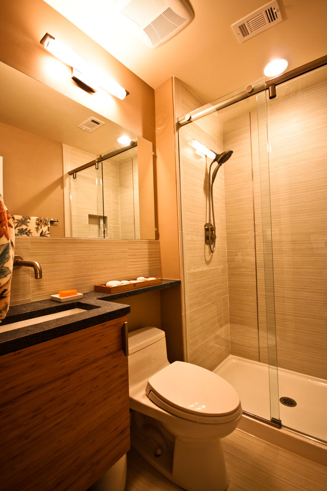 Modern inredning av ett litet badrum med dusch, med släta luckor, skåp i mellenmörkt trä, en dusch i en alkov, en toalettstol med hel cisternkåpa, beige väggar, ett undermonterad handfat och bänkskiva i akrylsten