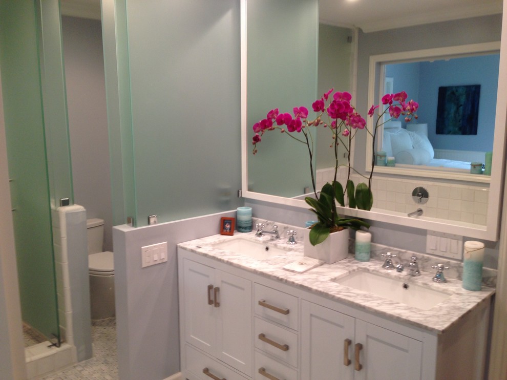 Cette image montre une petite salle de bain principale minimaliste avec des portes de placard blanches, une baignoire indépendante, WC séparés, un carrelage blanc, un carrelage de pierre, un mur bleu, un sol en marbre, un lavabo intégré et un plan de toilette en marbre.