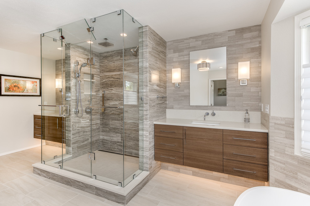 Inspiration for a large contemporary ensuite bathroom in Denver with flat-panel cabinets, light wood cabinets, a freestanding bath, a double shower, a wall mounted toilet, beige tiles, limestone tiles, grey walls, porcelain flooring, a submerged sink, engineered stone worktops, white floors, a hinged door and white worktops.