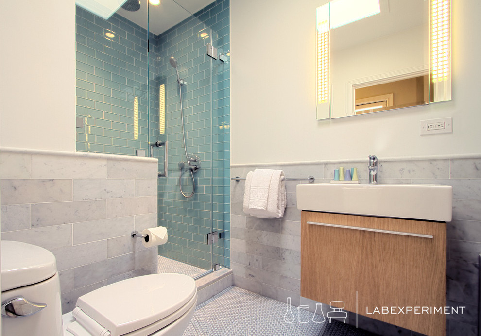 Imagen de cuarto de baño contemporáneo pequeño con lavabo integrado, armarios tipo mueble, puertas de armario de madera oscura, sanitario de una pieza, baldosas y/o azulejos azules, baldosas y/o azulejos de vidrio, paredes blancas, suelo con mosaicos de baldosas y ducha empotrada