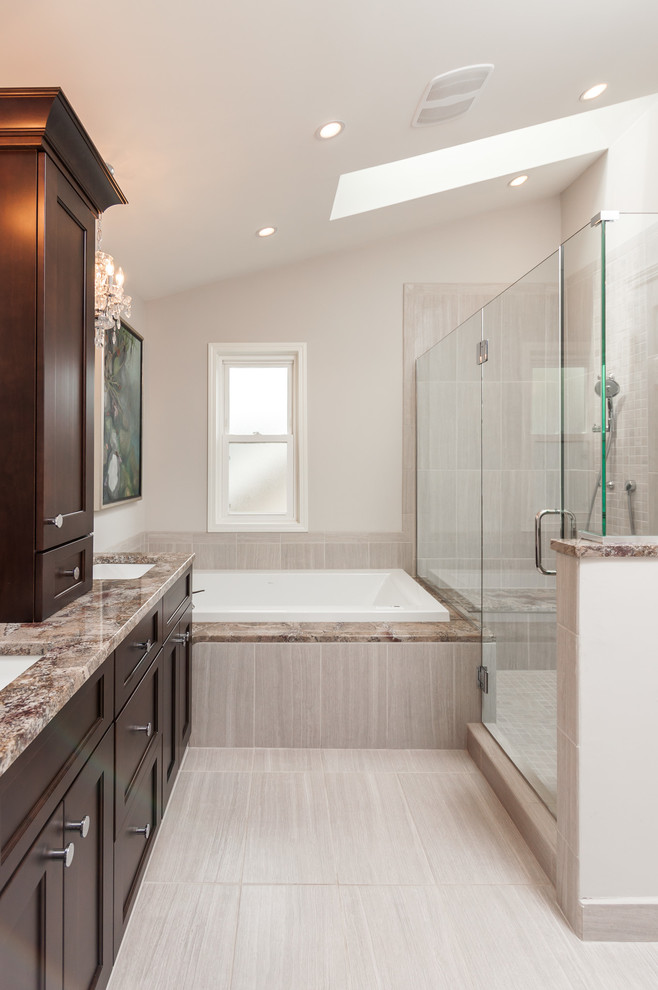 This is an example of a traditional ensuite bathroom in Detroit with a submerged sink, shaker cabinets, dark wood cabinets, granite worktops, a built-in bath, a one-piece toilet, grey tiles, porcelain tiles, grey walls and porcelain flooring.