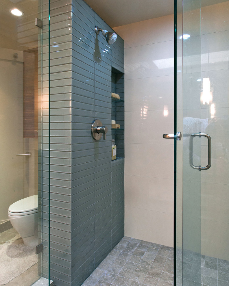 Mid-sized trendy master pebble tile marble floor and gray floor bathroom photo in San Francisco with flat-panel cabinets, medium tone wood cabinets, a two-piece toilet, beige walls, an undermount sink, solid surface countertops and a hinged shower door